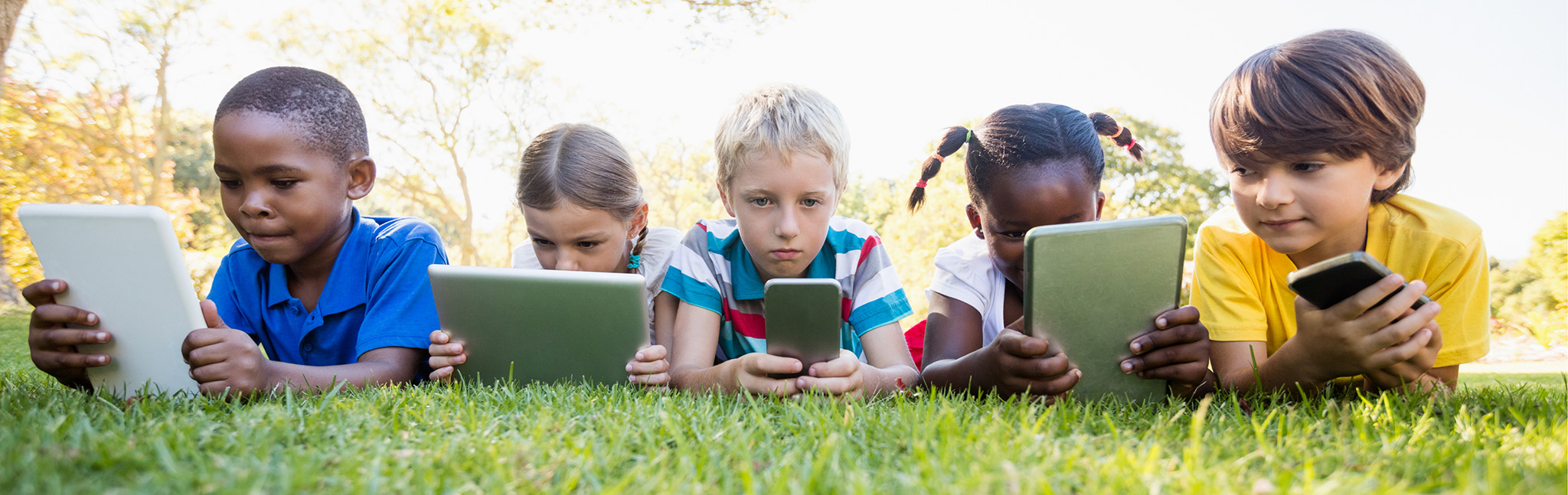 5 kids with technology on grassy lawn