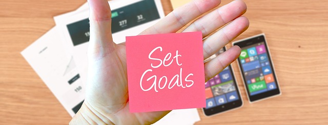 Hand with Set Goals stickie and mobile devices in the background