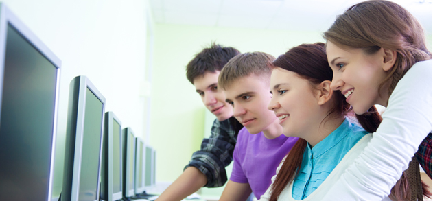 4 teens working on desktops together